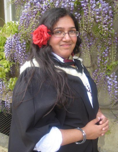 Shanika standing in her college grounds in her graduation gown