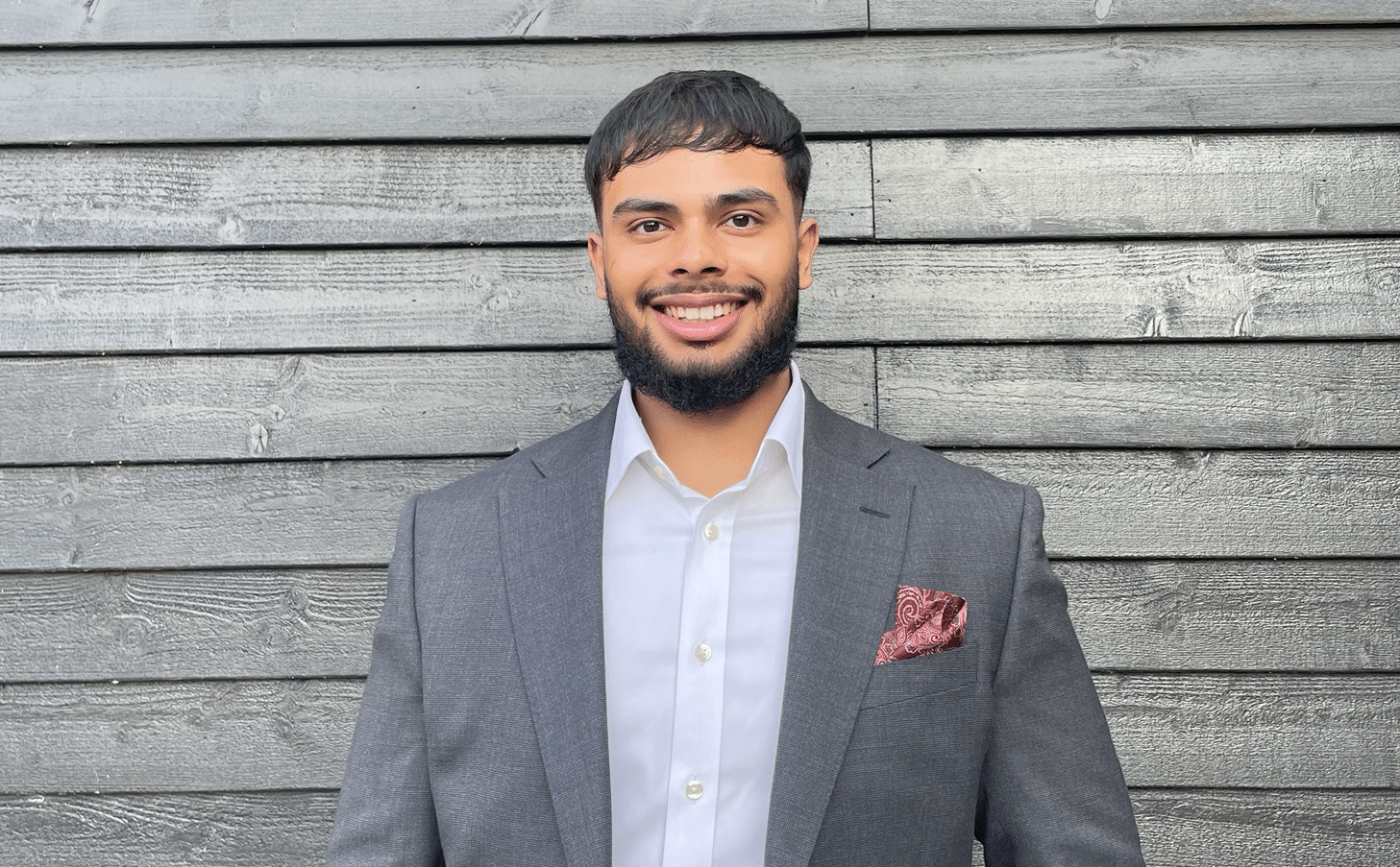 Man standing in front of a wall smiling.